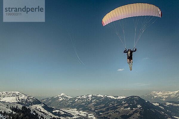 Mann fliegt im Winter in den österreichischen Alpen  Kitzbühel  Tirol  Österreich