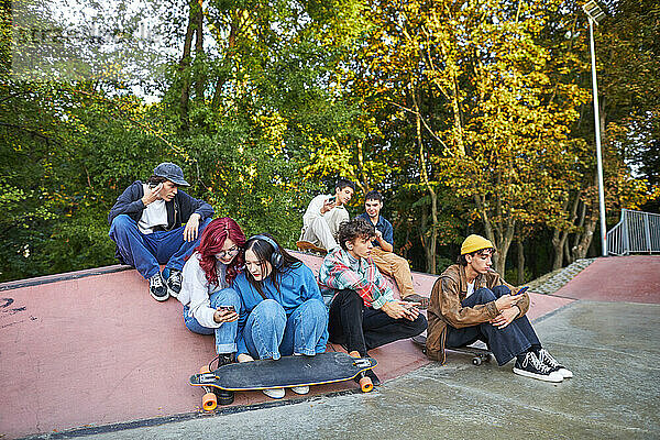 Gruppe junger Leute  die in einem Skatepark auf Telefone schauen