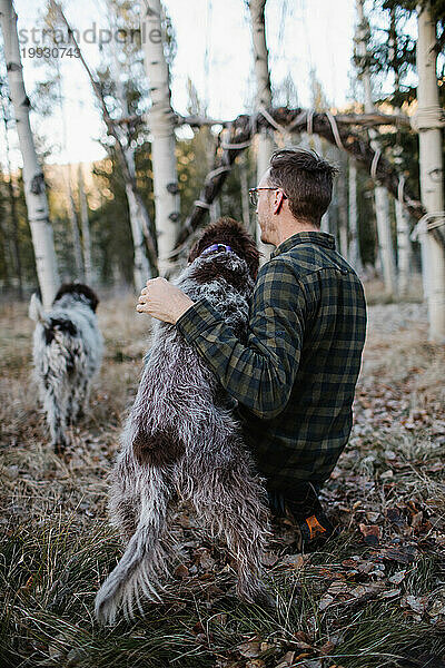 Mann und Griffon-Hund stehen zusammen im Wald von Idaho