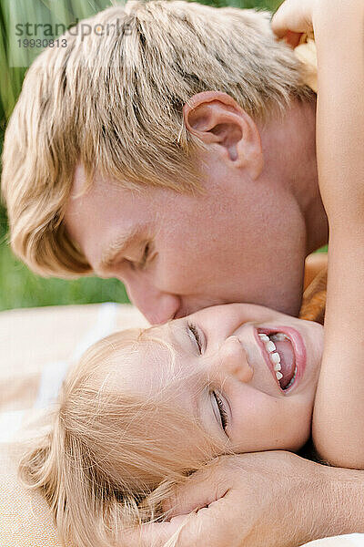 Vater umarmt und küsst zärtlich sein Baby  Mädchen lacht  Nahaufnahme