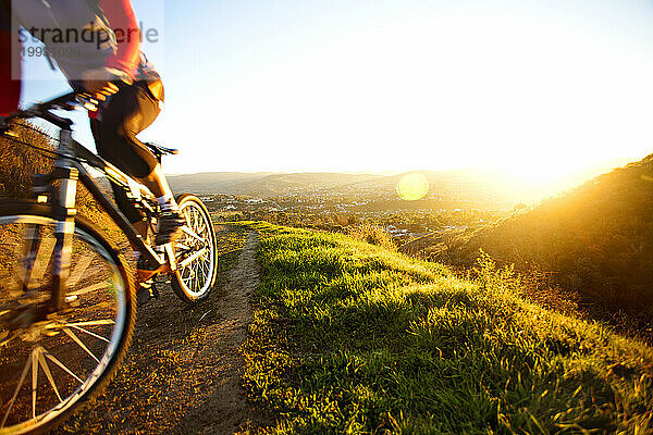Eine aktive Frau Mitte Zwanzig fährt bei Sonnenaufgang in Südkalifornien mit dem Mountainbike.