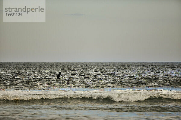 Eine Silhouette eines Surfers  der auf die Wellen auf dem Meer wartet