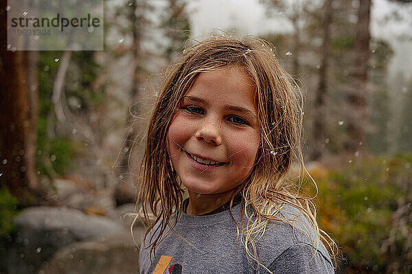 Lächelndes Tween-Porträt draußen mit Schneeflocken im Haar