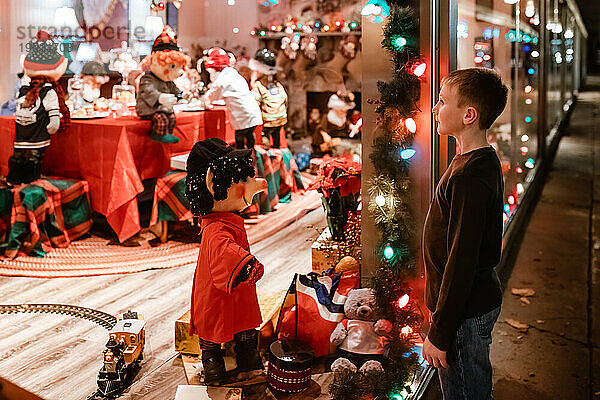 Kind schaut in weihnachtlich dekoriertes Schaufenster