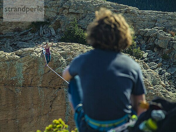 Frau beim Highlinen  während Freunde in Colorado zuschauen.