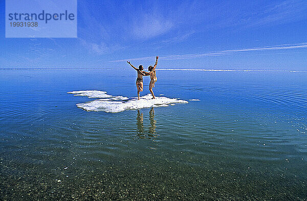 Nacktes junges Paar spielt auf einem Eisstrom im Arktischen Ozean  Nordwest-Territorien  Kanada.