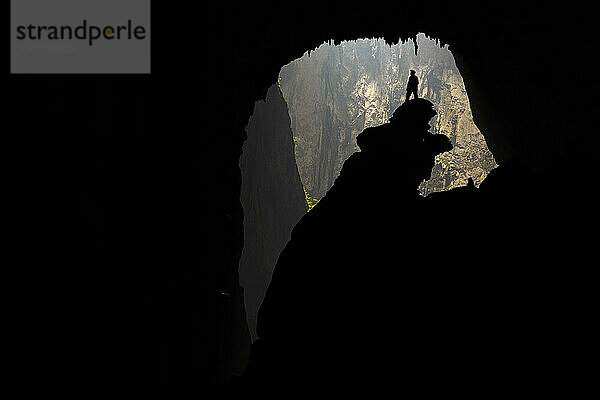 Die Silhouette eines Höhlenforschers  der auf der Hand des Hundes in Hang Son Doong steht.