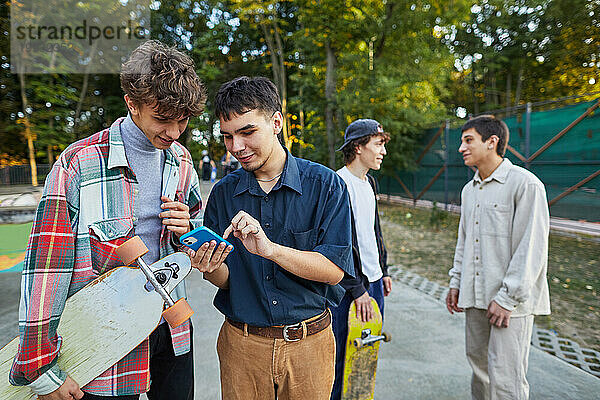Junge Leute schauen im Skatepark auf das Telefon