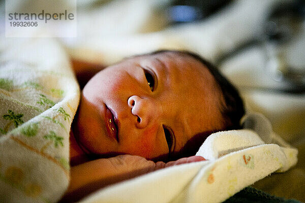 Ein neugeborener Junge liegt im Bett  während Hebammen ihre Neugeborenenuntersuchungen durchführen.