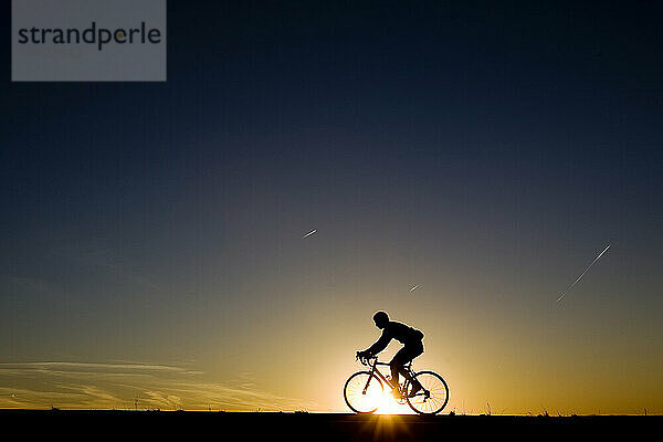 Die Silhouette eines Mannes zeichnete sich vor der untergehenden Sonne ab  während er mit seinem Rennrad in Albuquerque  New Mexico  unterwegs war.