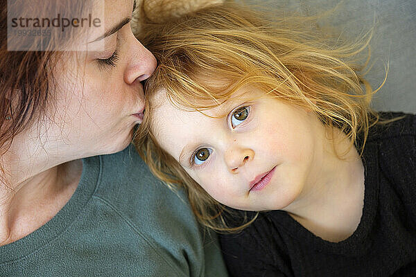 Liebevolle Mutter umarmt ihre rothaarige Tochter mit positiven Emotionen
