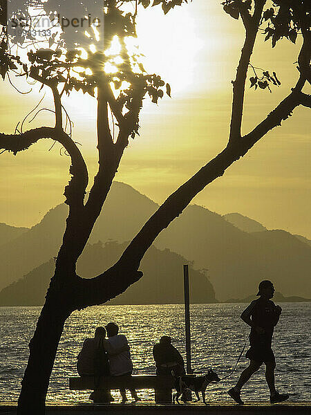 Silhouette von Menschen vor einem Meer bei Sonnenaufgang  Copacabana  Rio De Janeiro  Brasilien.