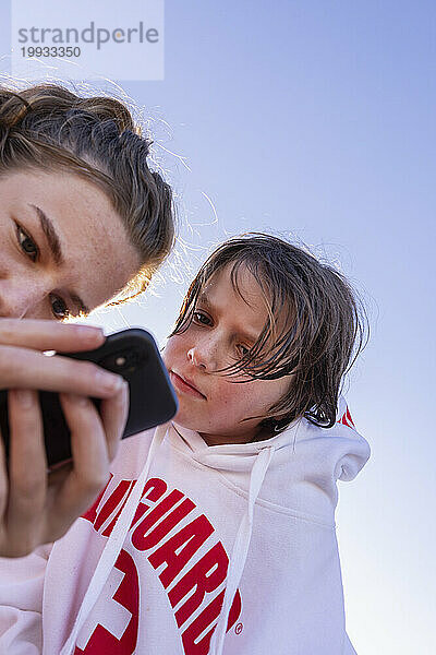 Bruder (10-11) und Schwester (16-17) schauen aufs Smartphone