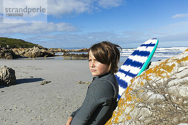 Junge (10-11) mit Bodyboard entspannt am Voelklip Beach