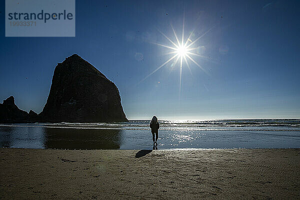 USA  Oregon  Silhouette einer Frau  die in der Nähe des Haystack Rock am Cannon Beach steht