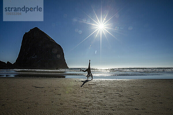 USA  Oregon  Silhouette einer Frau beim Radschlagen in der Nähe des Haystack Rock am Cannon Beach