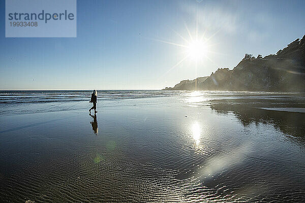 USA  Oregon  Newport  Frau läuft im Sonnenlicht am nassen Sandstrand