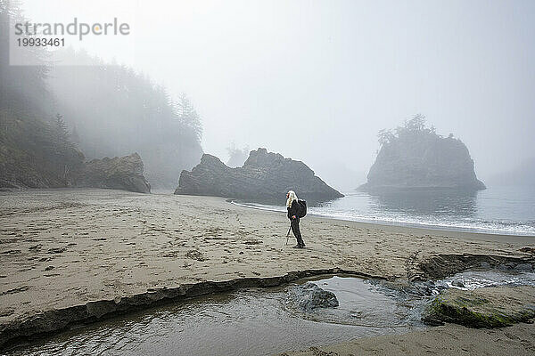 USA  Oregon  Brookings  Ältere Frau steht am Strand in der Nähe eines Baches