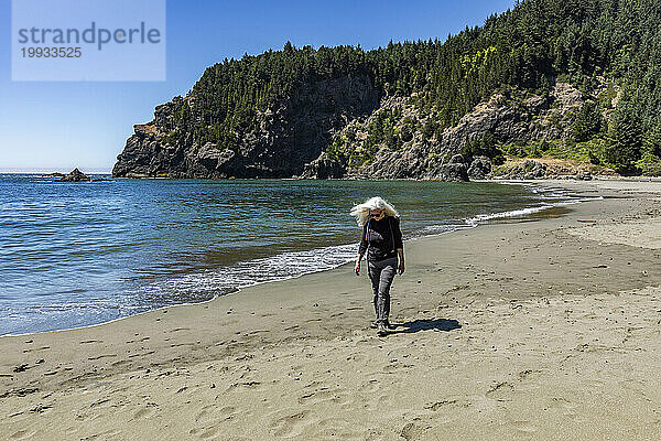 USA  Oregon  Brookings  Seniorin geht an einem sonnigen Tag am Strand spazieren