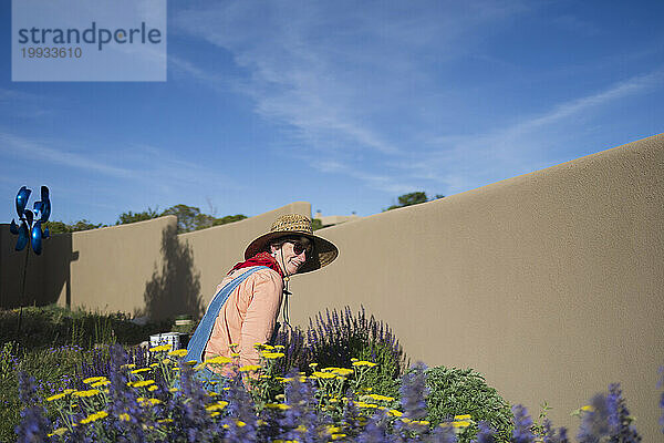 USA  New Mexico  Santa Fe  Frau mit Strohhut und Jeansoverall bei der Gartenarbeit