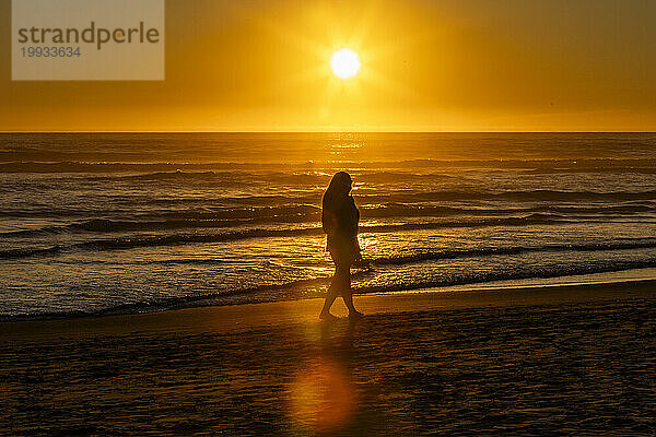 Silhouette einer Frau  die am Cannon Beach entlang geht