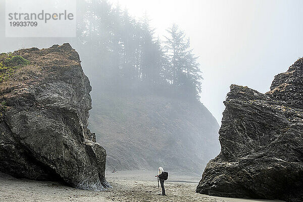 USA  Oregon  Brookings  Ältere Frau steht zwischen Felsen am Strand
