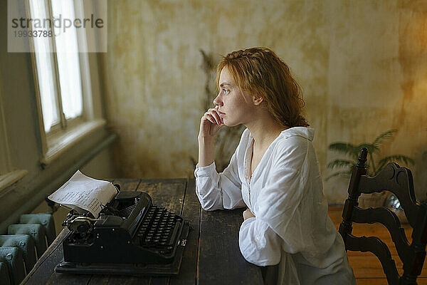 Seitenansicht einer Frau  die zu Hause eine Vintage-Schreibmaschine benutzt