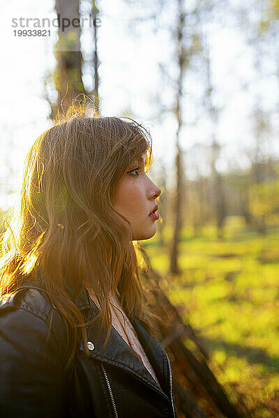 Seitenansicht einer Frau  die an einem sonnigen Tag auf den Wald blickt