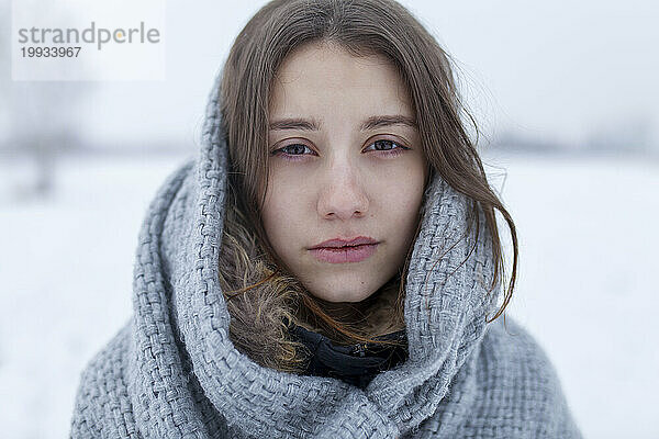 Porträt einer ernsthaften Frau mit Schal in winterlicher Landschaft