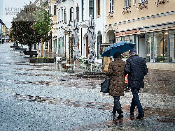 Paar ältere Menschen gehen im Regen in der Stadt spazieren