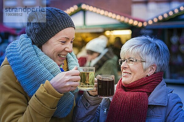 Zwei Frauen stehen auf dem Weihnachtsmarkt und trinken Glühwein