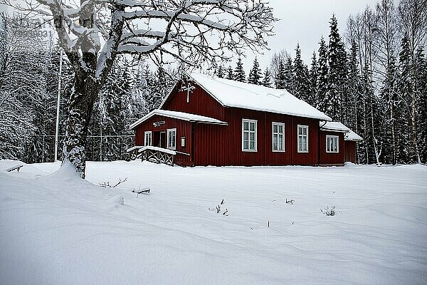 Typisches rotes schwedisches Haus. Holtzhaus in einer Winterlandschaft mit Eis und Schnee. Kleine Siedlung mitten im verschneiten Wald. Landschaftsaufnahme in Schweden