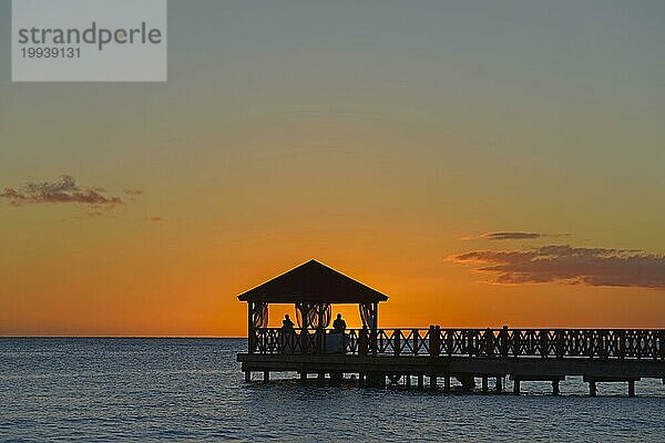 Silhouette eines Stegs gegen den orange gefärbten Himmel bei Dämmerung ohne sichtbare Menschen  Strand Dominicus  Bayahibe  Dominikanische Republik  Hispaniola  Karibik  Amerika  Mittelamerika