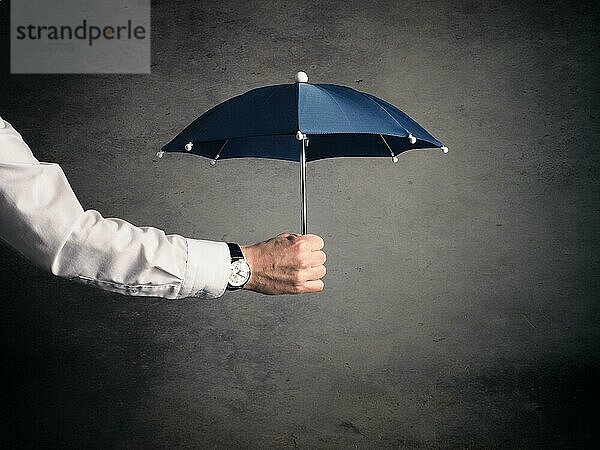 Geschäftsmann hält einen kleinen blaün Regenschirm  Schutz oder Sicherheit Konzept Bild
