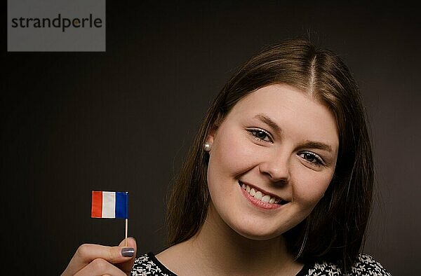Schöne lächelnde Frau mit einer kleinen Flagge von Frankreich