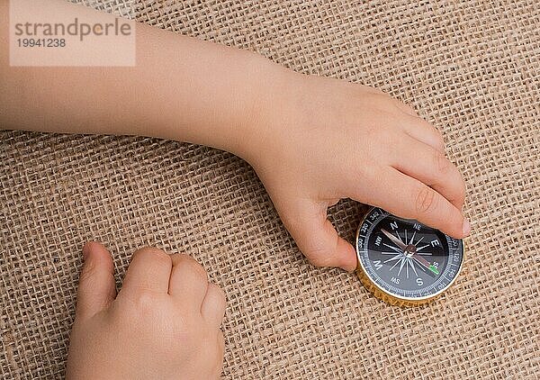 Kompass  Schlüssel und ein herzförmiges Objekt neben einer Hand