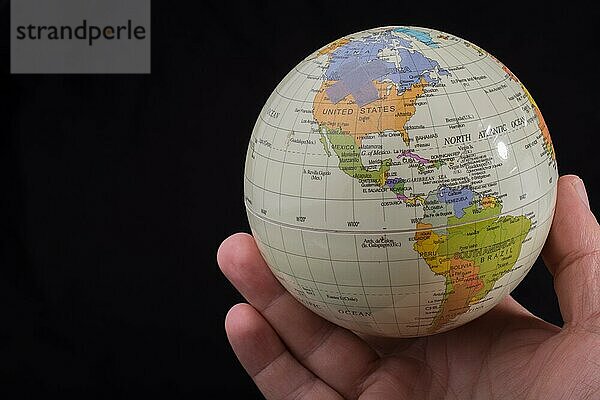 Eine Hand hält einen Globus mit einer Karte in der Hand