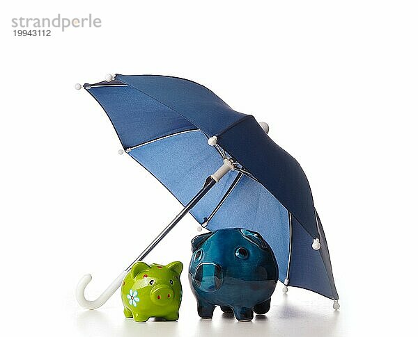 Zwei alte Keramik Sparschwein unter einem Regenschirm  finanzielle Konzept der Schutz der Ersparnisse  auf einem weißen Hintergrund