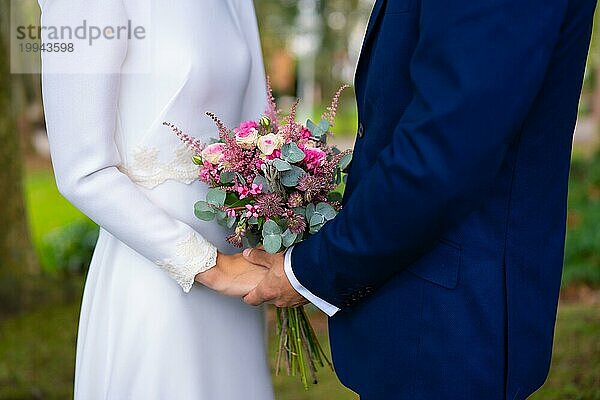 Detail der Hände bei der Hochzeit der glücklichen Braut und Bräutigam mit Blumen  Ehe Porträts