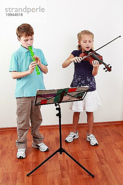 Niedliche Kinder spielen Flöte und Geige zusammen