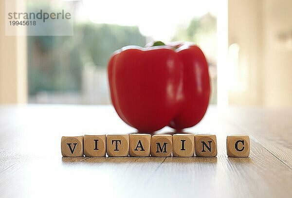 Der Schriftzug Vitamin C mit einer frischen Biopaprika auf einem Küchentisch  selektiver Fokus im Vordergrund  Konzept der gesunden Ernährung