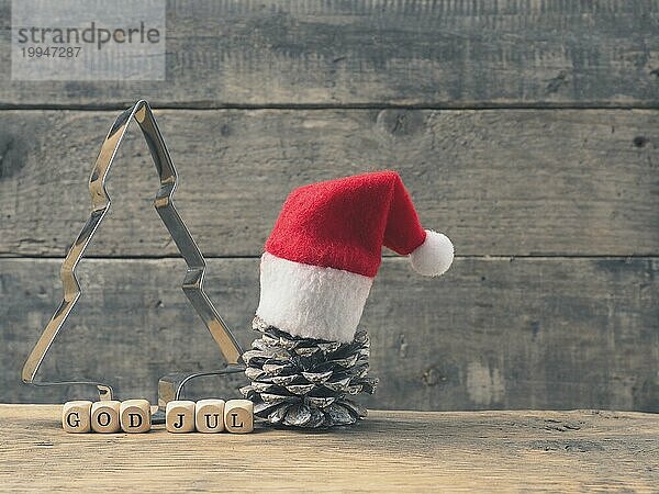 Gott Jul auf Holzwürfeln  skandinavische Frohe Weihnachten  Weihnachtshintergrund mit einer baumförmigen Backform und einem Tannenzapfen auf einem rustikalen Holzbrett