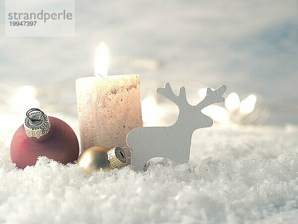 Weihnachtsdekoration im Schnee mit Kerze  selektiver Fokus auf Weihnachtsbaumkugeln im Vordergrund  Urlaub Hintergrund