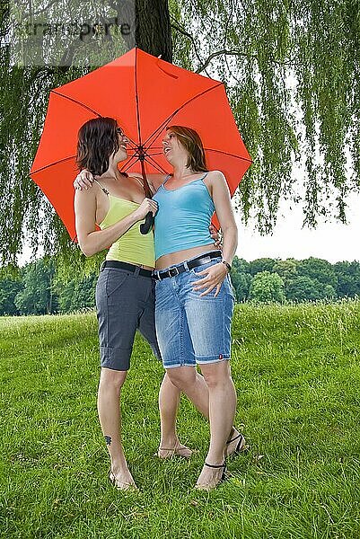 2 junge Frauen unter einem roten Regenschirm