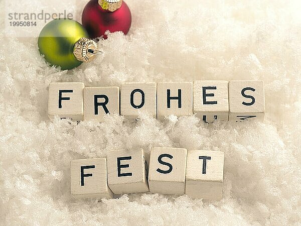 Frohes Fest  Holzklötze mit bunten Christbaumkugeln im Schnee