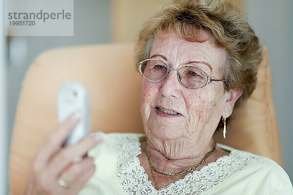 Rentnerin betrachtet vergnügt ihr Handy