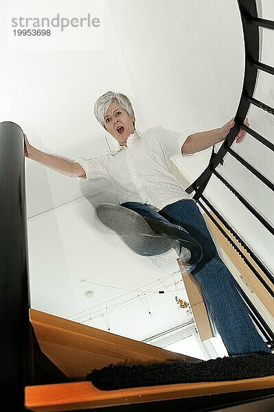 Frau steht auf einer Treppe und tritt mit dem Fuß nach unten Richtung Betrachter