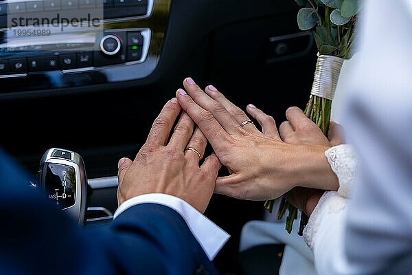 Hände von Braut und Bräutigam mit Ringen in einem Auto bei einer schönen Hochzeit  Hochzeitsfeier