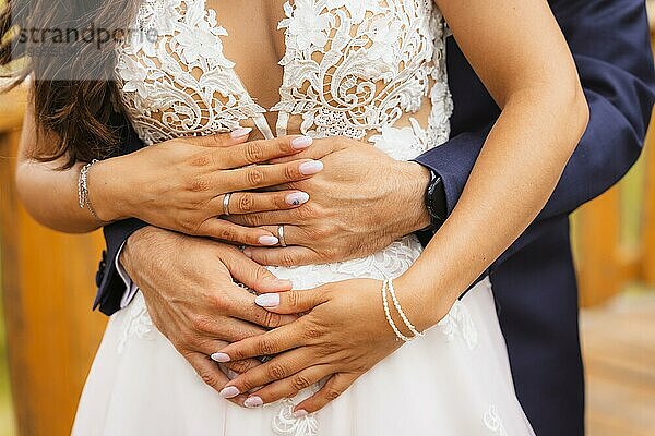 Hände von Braut und Bräutigam umarmt mit Ringen bei einer schönen Hochzeit  Trauung