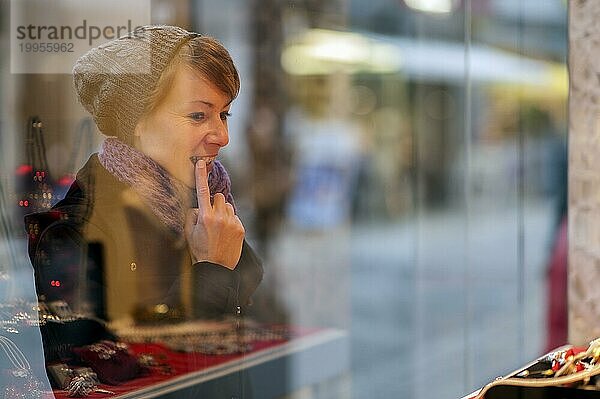 Junge Frau betrachtet das Schaufenster eines Juweliergeschäftes